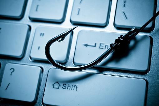 a fish hook on computer keyboard representing phishing attack on computer system